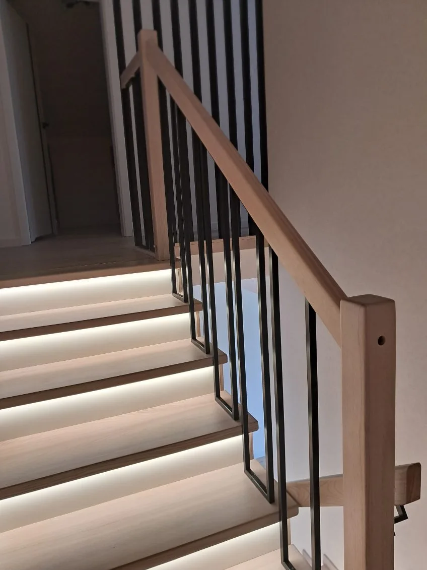 Schody drewniane z czarną balustradą i LED